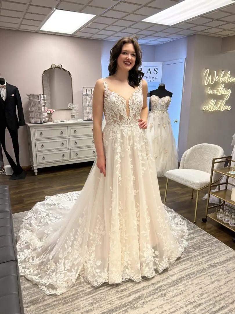 Woman wearing lace wedding gown in bridal shop