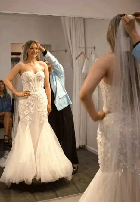 Bride trying on wedding dress in mirror.